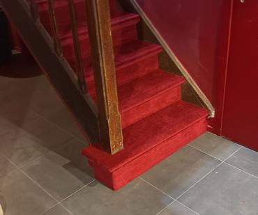 Départ d'escalier rénové avec un tapis rouge